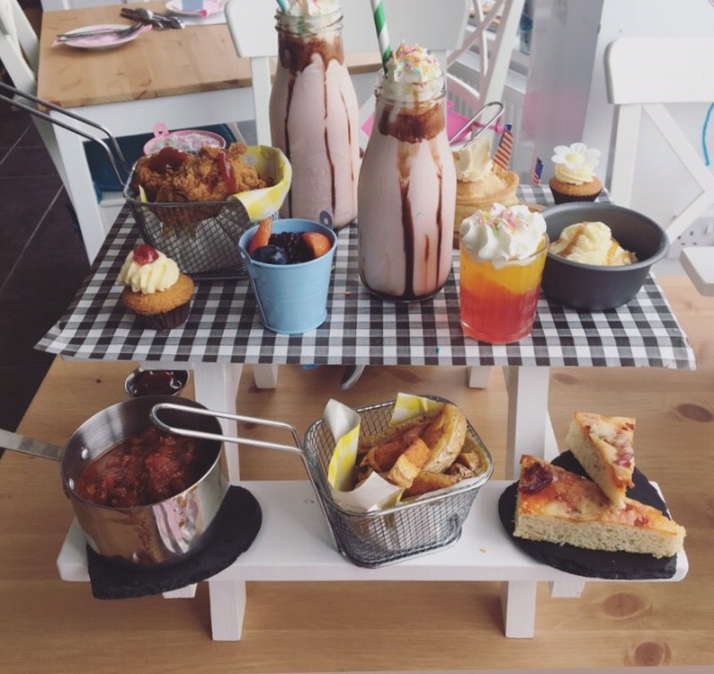 Kids Food Displayed on a Picnic Bench - Menu Included Meatballs in Tomato Sauce, Mini Cheese and Tomato Pizzas and Fries, Jelly and Ice Cream, a Fruit Pot, a Mini Cupcake and a Milkshake