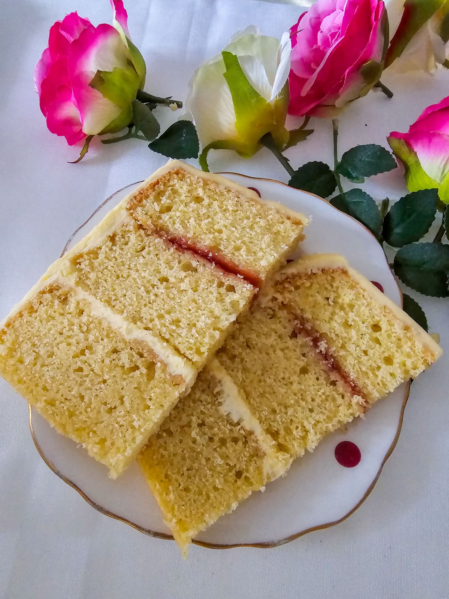 Two slices of layered birthday cake on vintage red polka dot plate with florals