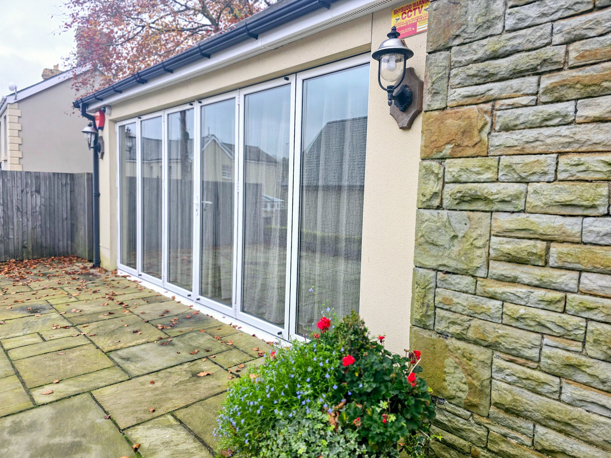 Close-up of venue extension with floor-to-ceiling windows, stonework, and floral landscaping
