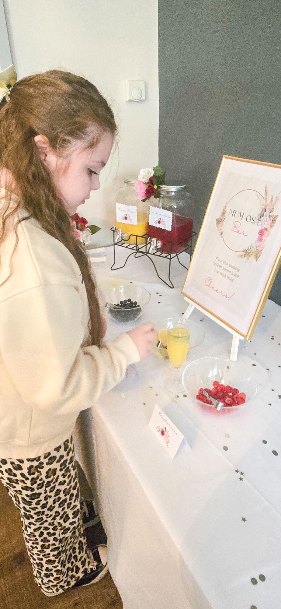 Young girl serving orange Mum-osa with fruit garnishes at drinks station